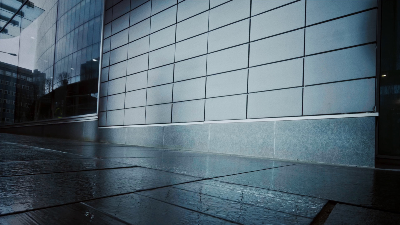 a wet sidewalk next to a building on a rainy day