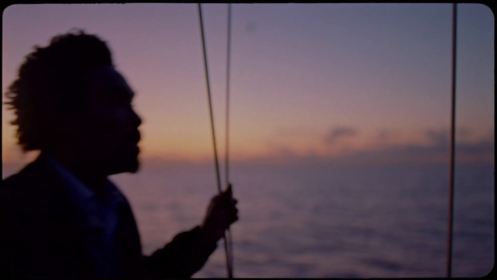 a silhouette of a person on a boat at sunset