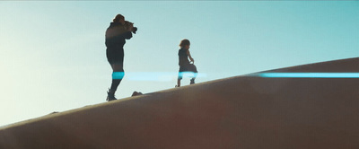 a couple of people standing on top of a sand dune