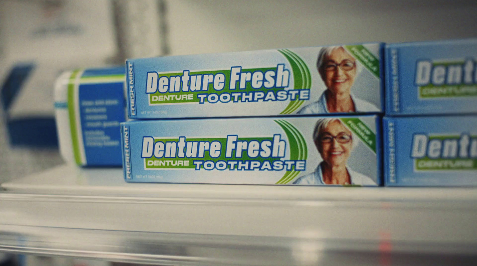 three boxes of denture fresh toothpaste sitting on a shelf