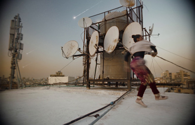 a man is running on a roof with satellite dishes in the background