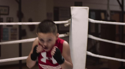 a young boy wearing a red shirt and boxing gloves