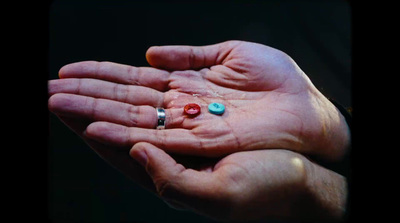 a person's hand holding three different colored beads