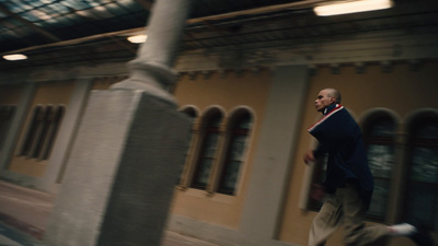 a man walking down a street past a tall building