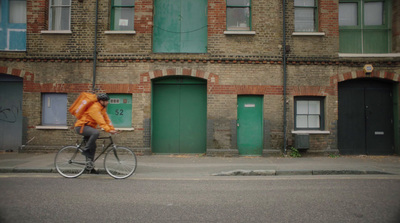 a man riding a bike down a street past a tall brick building