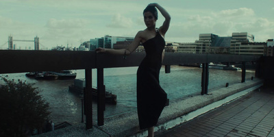 a woman in a black dress leaning on a rail