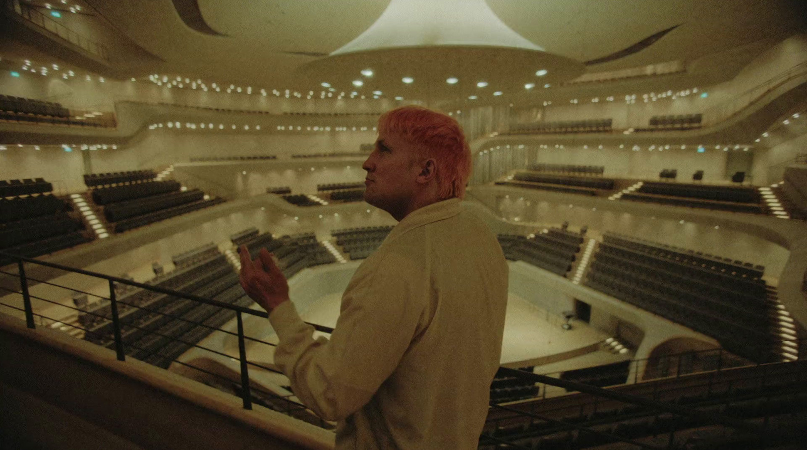 a man with red hair standing in front of a railing