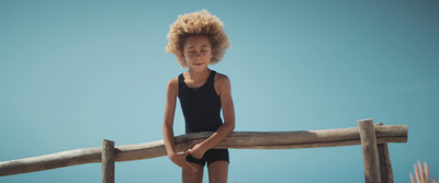 a little girl standing on a wooden fence