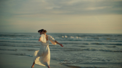 a woman in a white dress is running on the beach