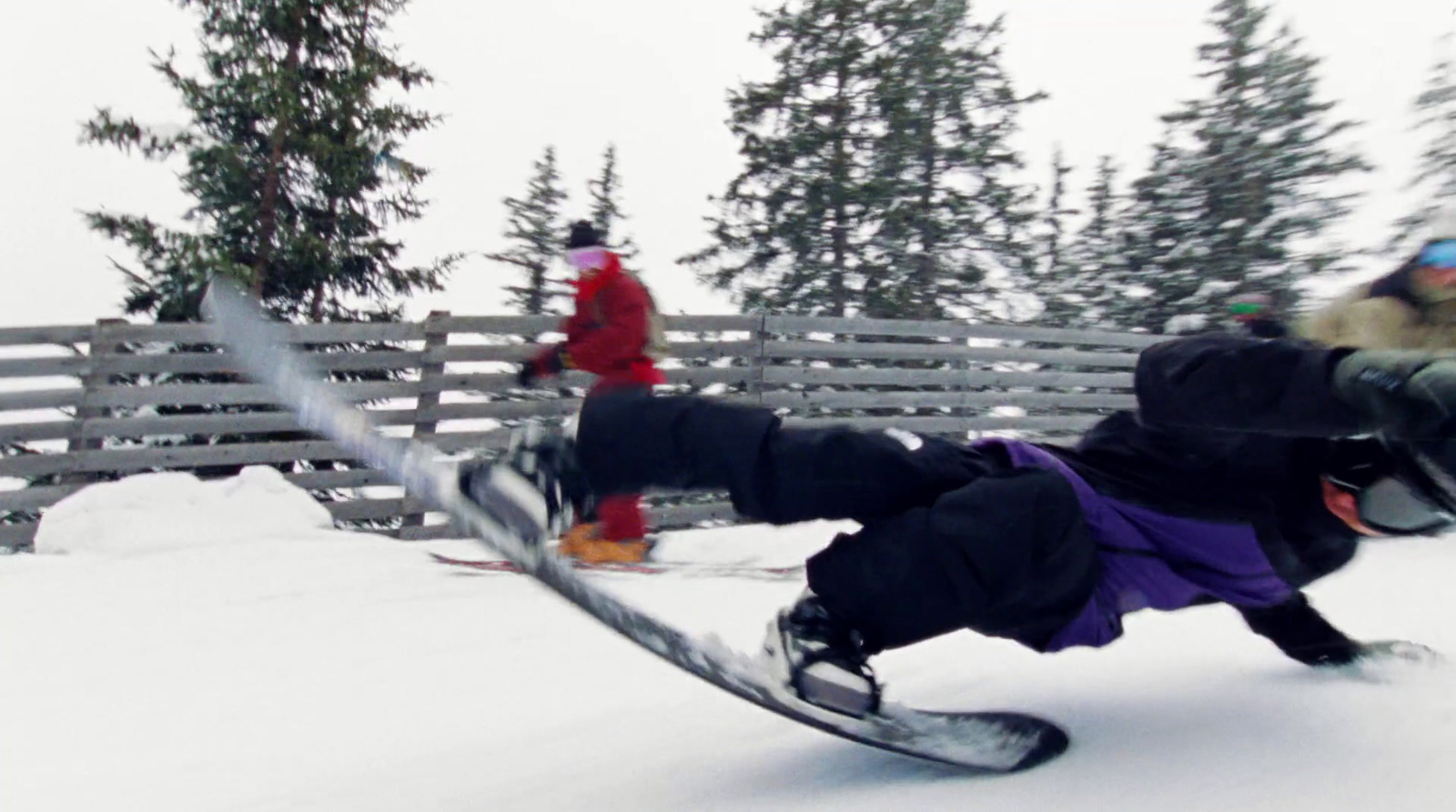 a man riding a snowboard down the side of a snow covered slope