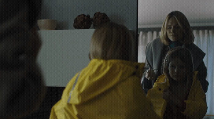 a woman standing in front of a mirror brushing her hair