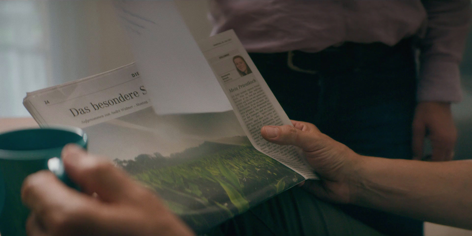 a person holding a magazine and a cup of coffee