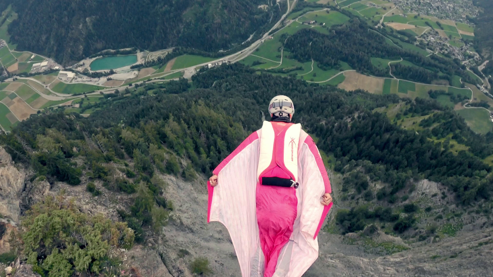 a woman in a pink dress standing on top of a mountain