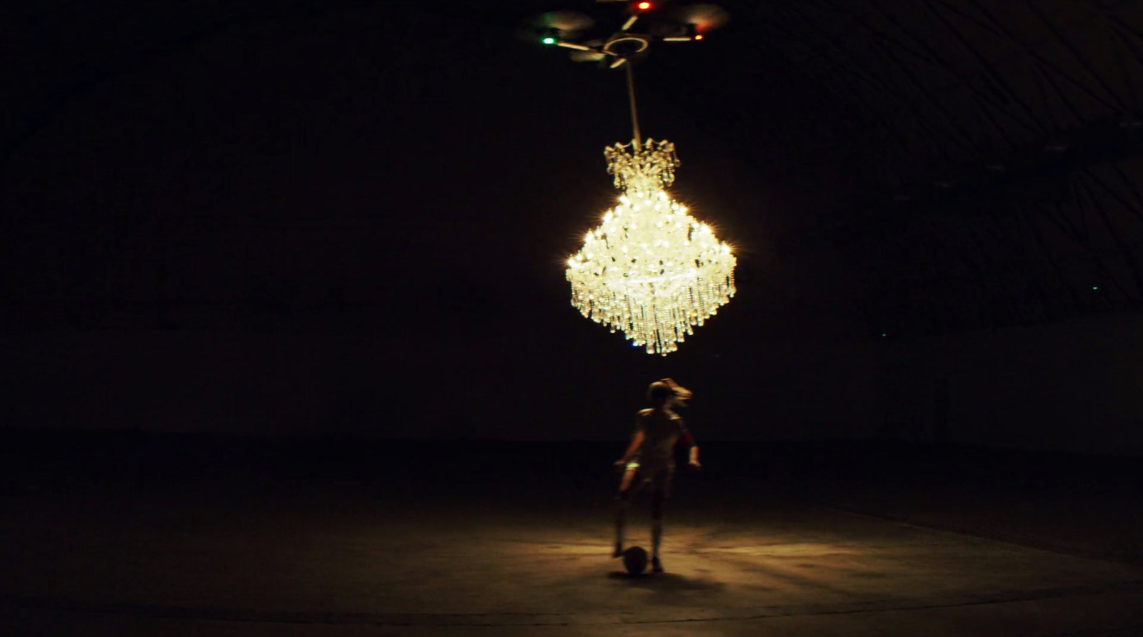 a person standing in a dark room with a chandelier hanging from the ceiling