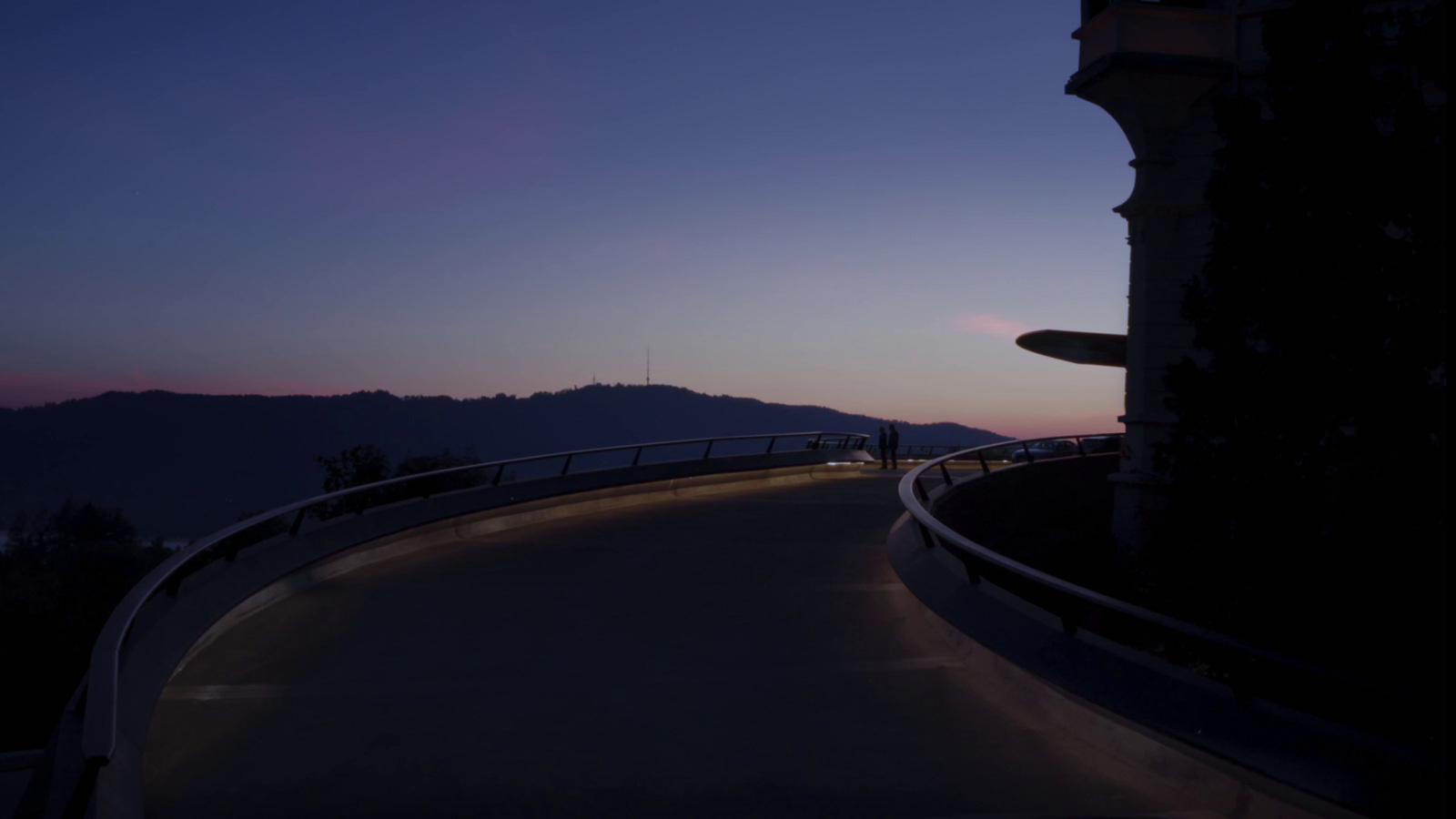 a curved road at night with mountains in the background