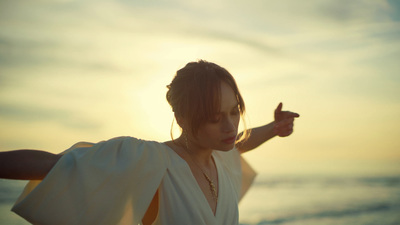 a woman in a white dress pointing at the sun