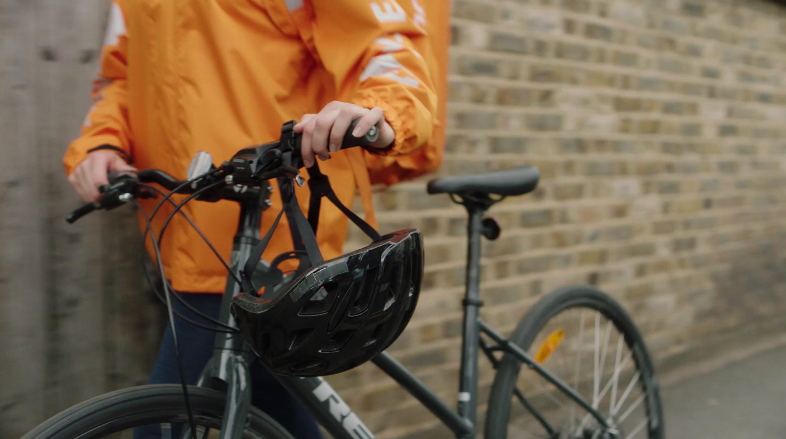 a man in an orange jacket is standing next to a bicycle