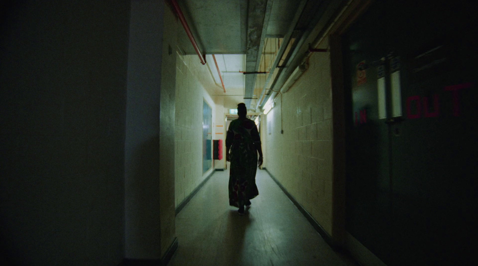 a person walking down a long hallway at night