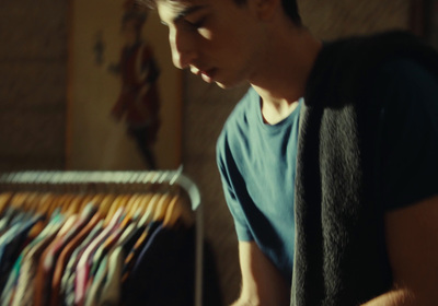 a man standing in front of a rack of shirts