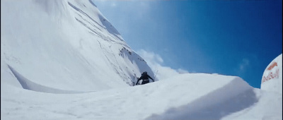 a man riding a snowboard down the side of a snow covered slope