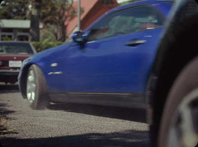 a blue car driving down a street next to a building