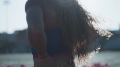 a man with long hair standing in front of a body of water