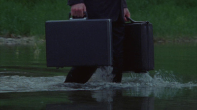 a man walking through a river carrying a briefcase