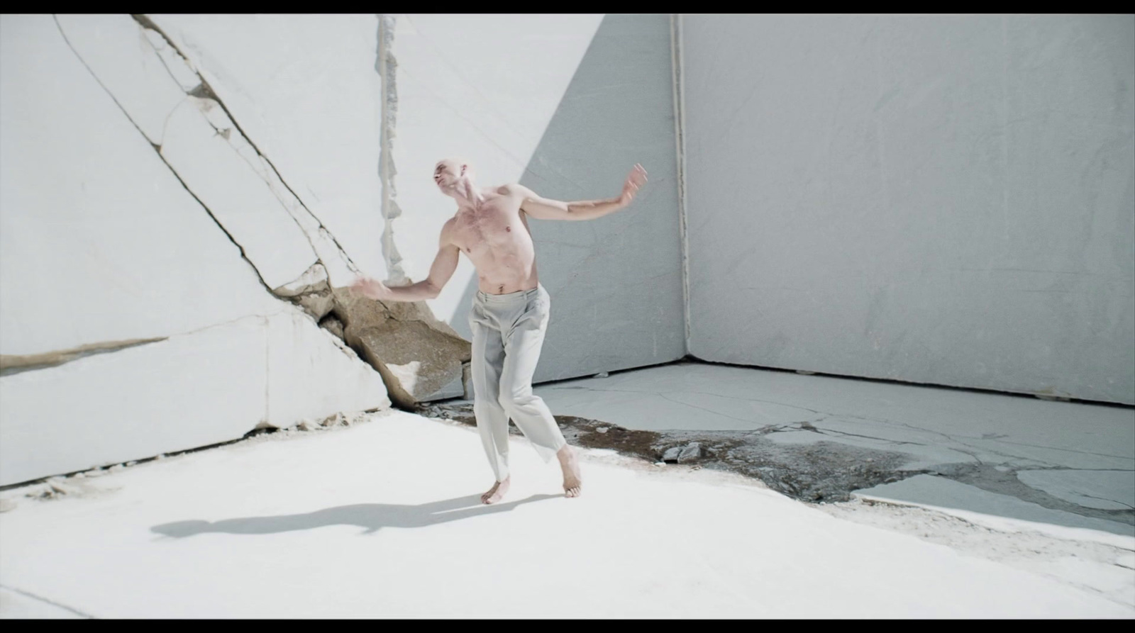 a shirtless man standing in front of a white wall