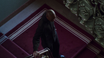 a man in a suit and tie walking down a stair case