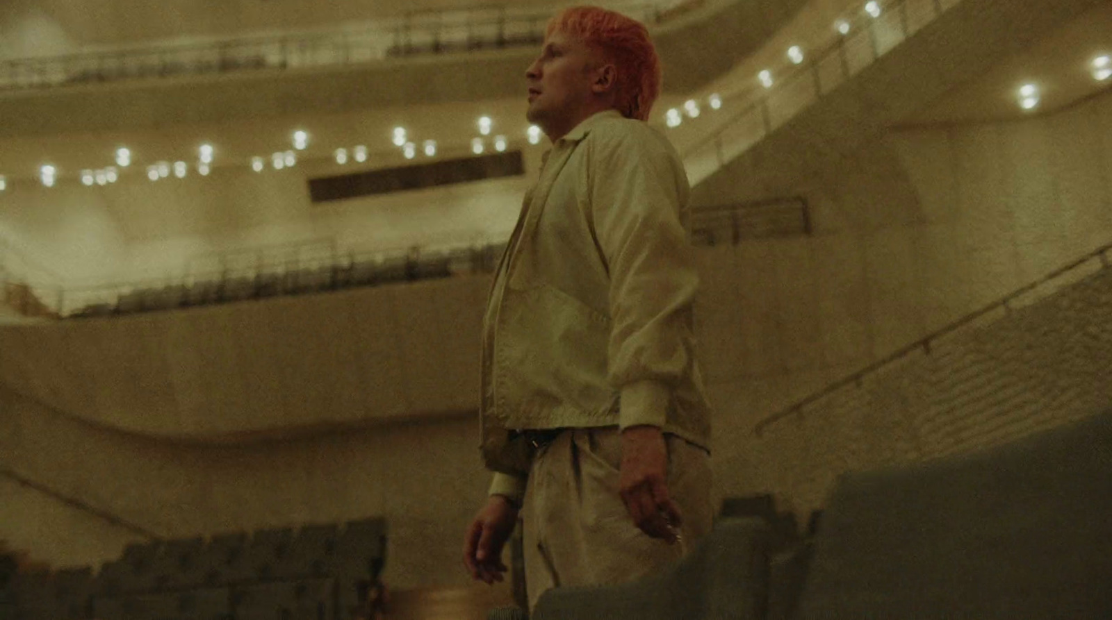 a man with red hair standing in front of a stage