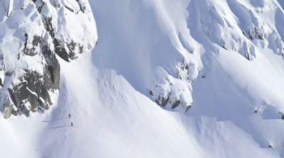 a man riding skis down the side of a snow covered mountain