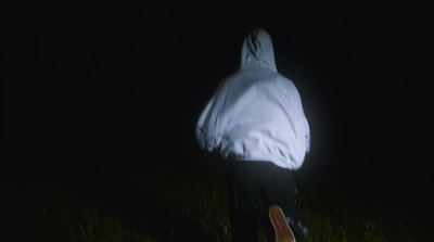 a person in a white jacket walking in the dark