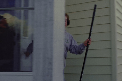 a woman standing outside of a house holding a pole