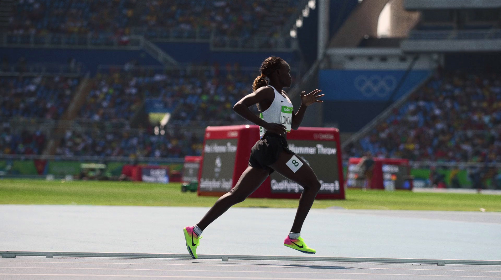 a woman running on a track in front of a crowd