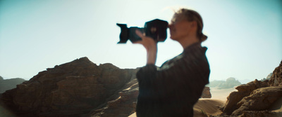 a woman holding a camera up in the air