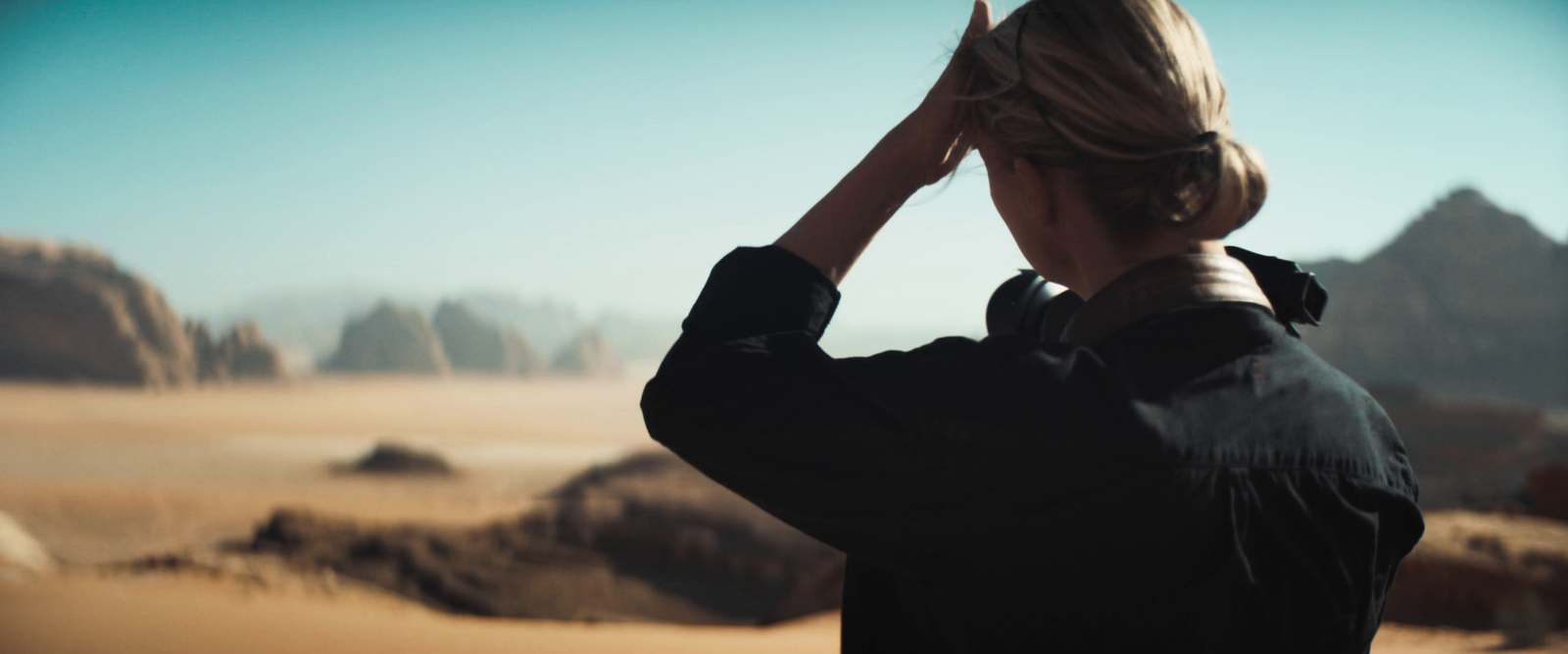 a woman standing in the desert with her hands on her head