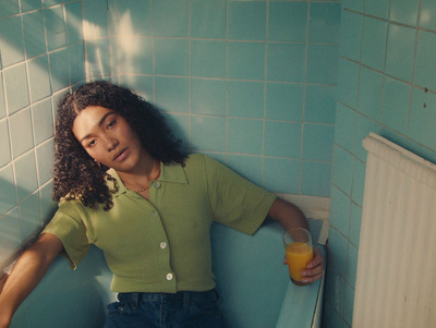 a woman in a green shirt leaning against a wall