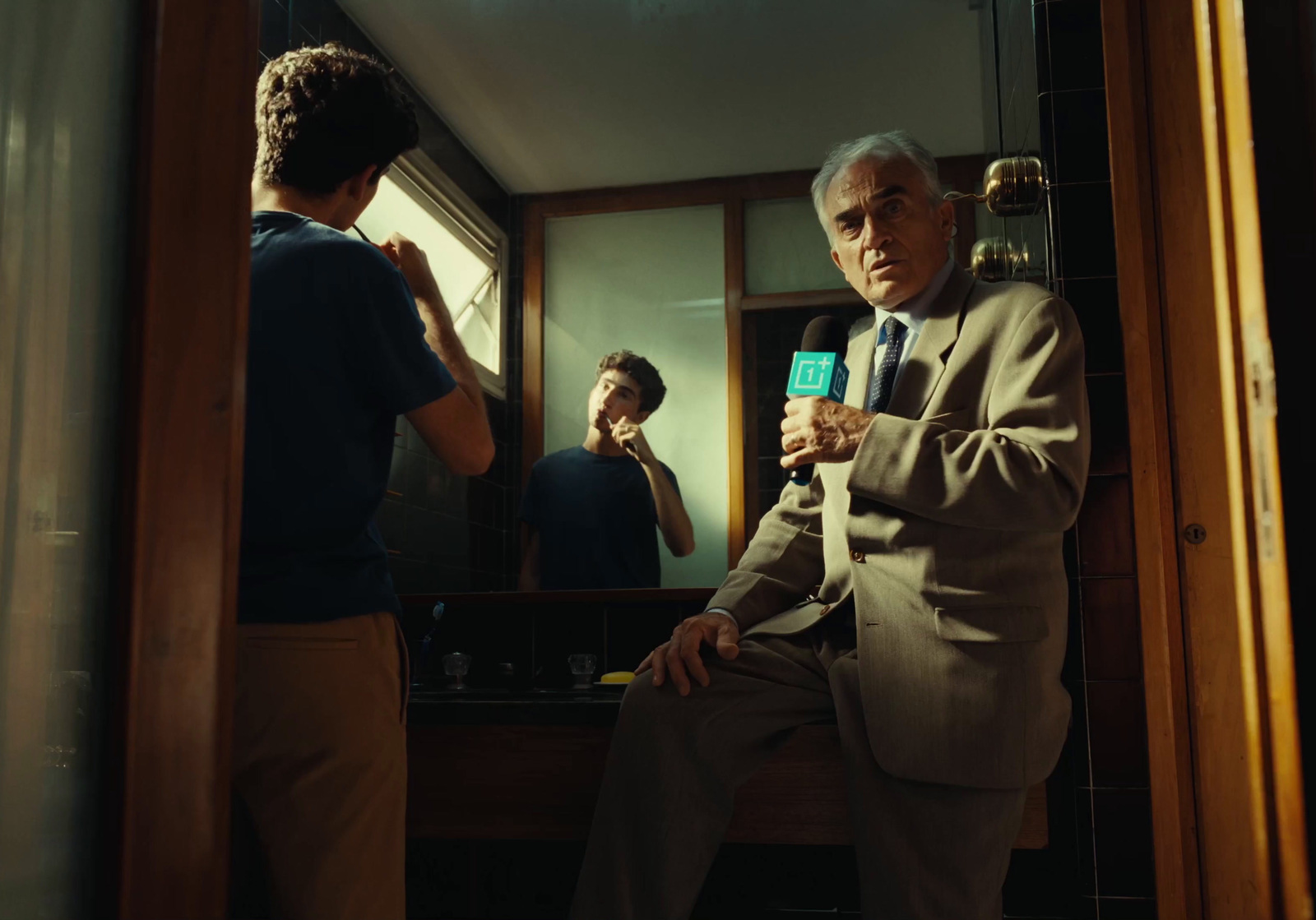 a man sitting in front of a mirror holding a microphone