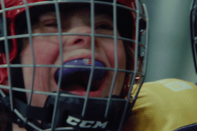 a young boy wearing a catchers mask and holding a ball in his mouth