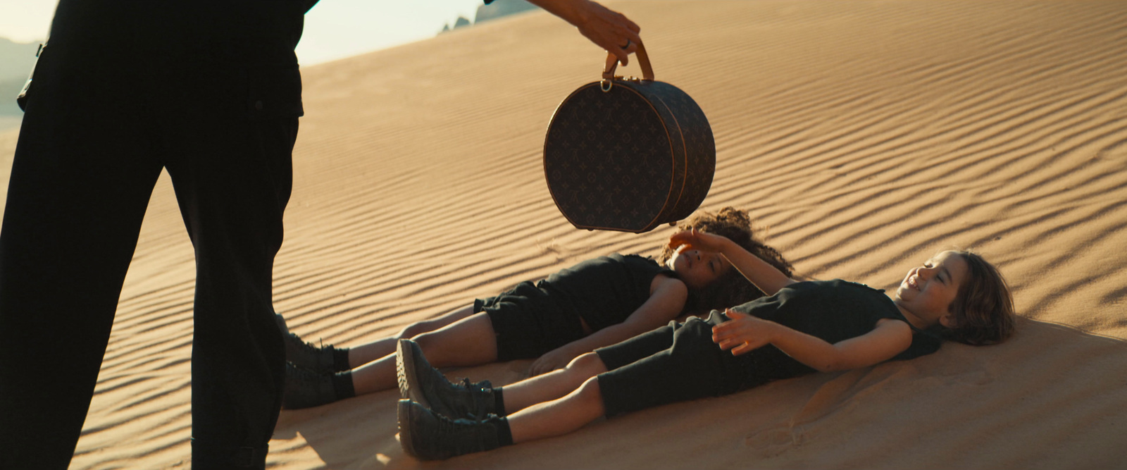 a woman is laying on the sand with a suitcase