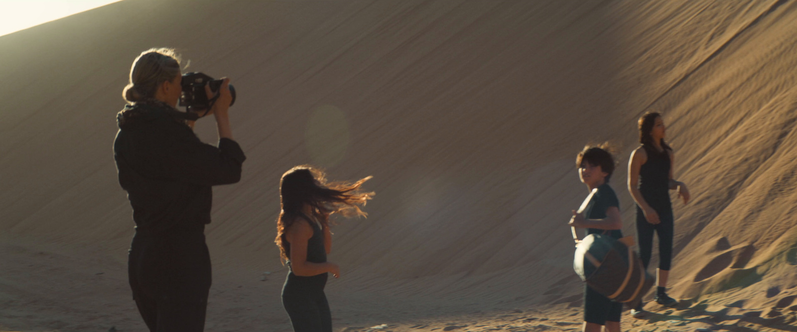 a group of people standing on top of a sandy hill