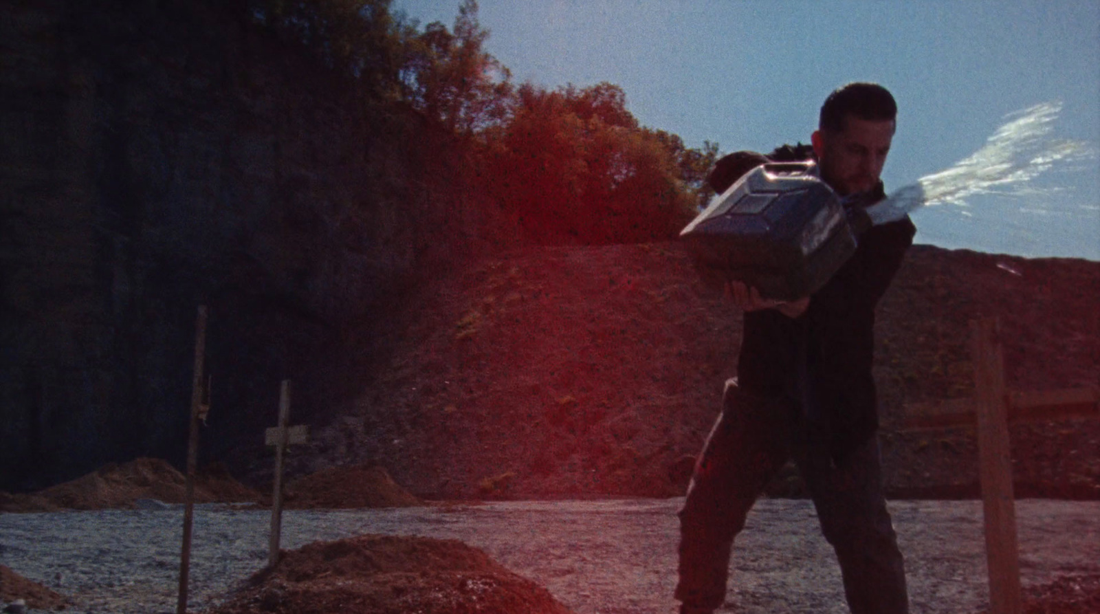 a man carrying a bag of luggage across a dirt field