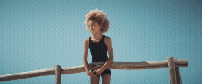 a young girl standing on a wooden fence