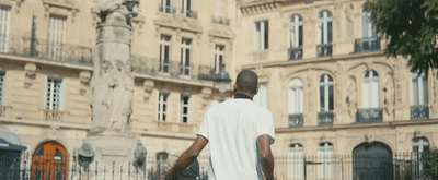 a man walking down a street past a tall building