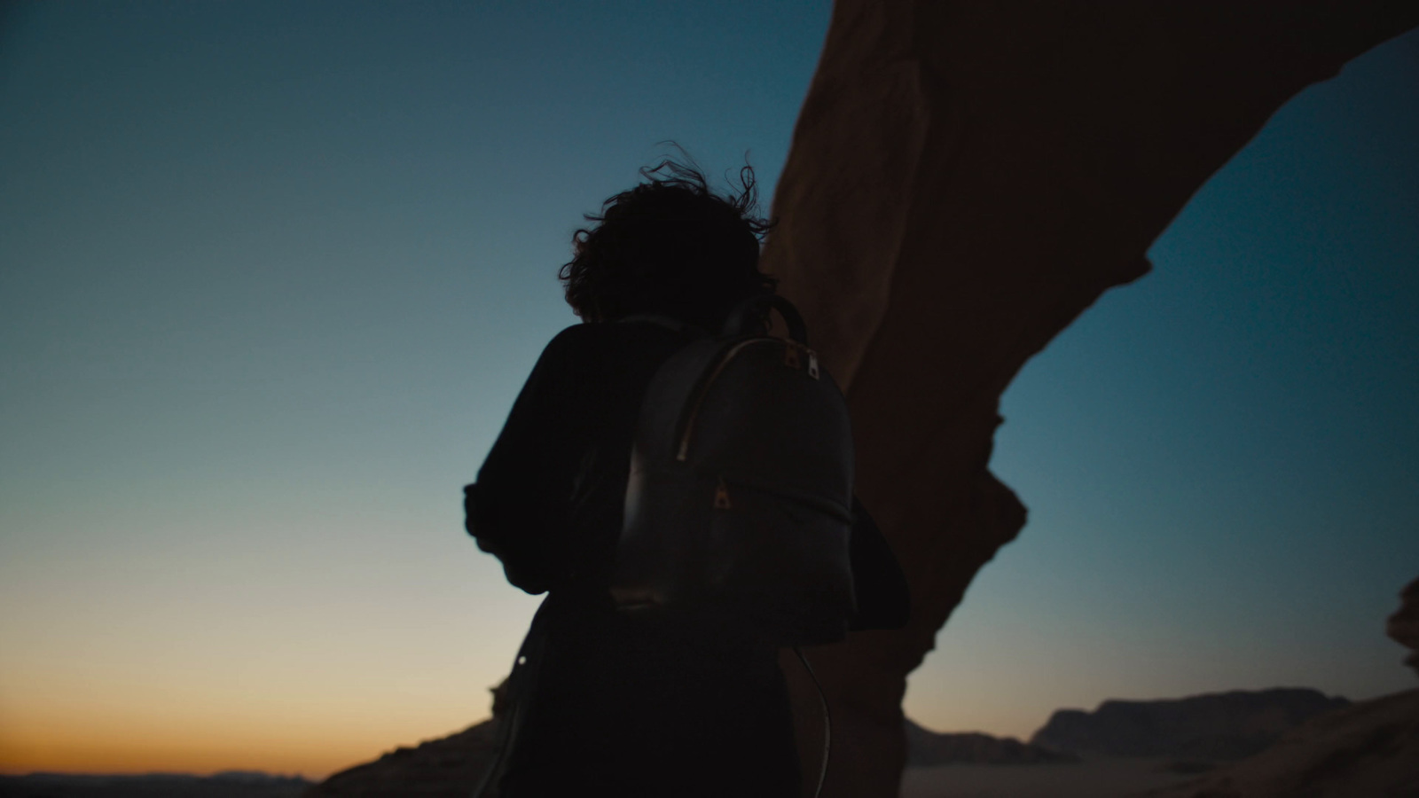 a person standing next to a large rock