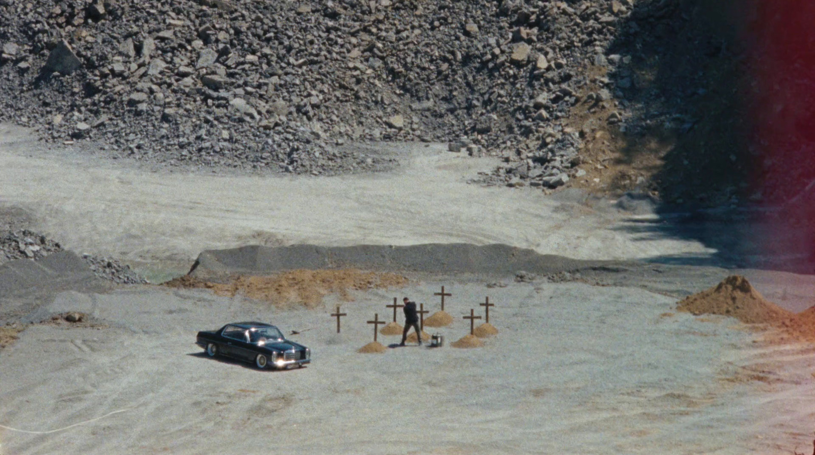 a car is parked in the middle of a dirt field