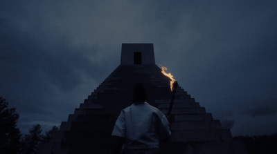 a person standing in front of a building with a fire on it