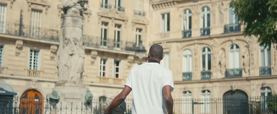 a man walking down a street past a tall building