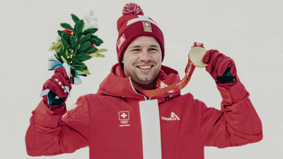 a man in a red jacket holding a gold medal