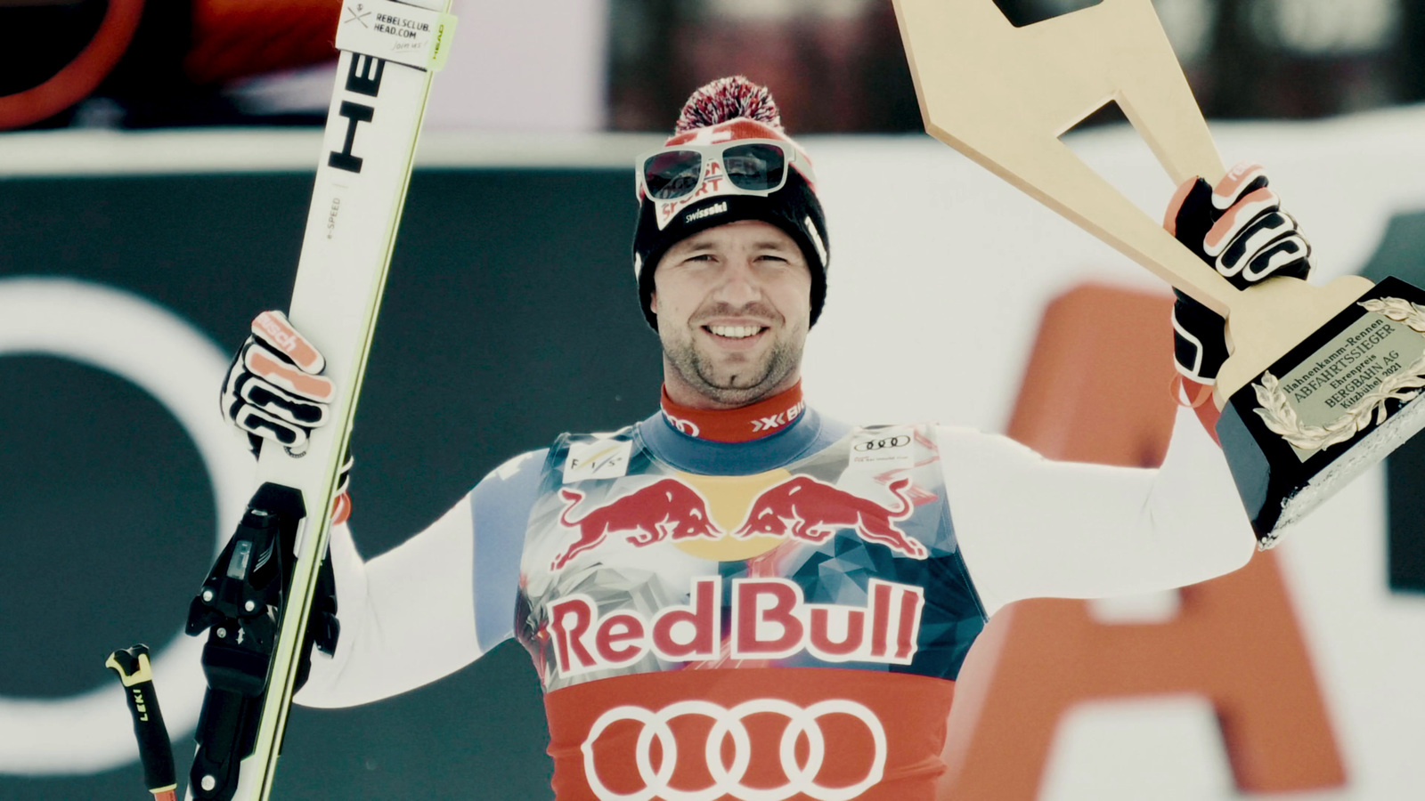 a man holding a pair of skis and a trophy